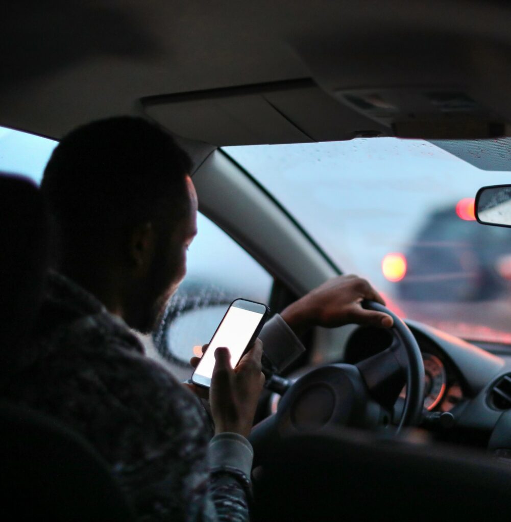 Man using his phone while driving in the rain.