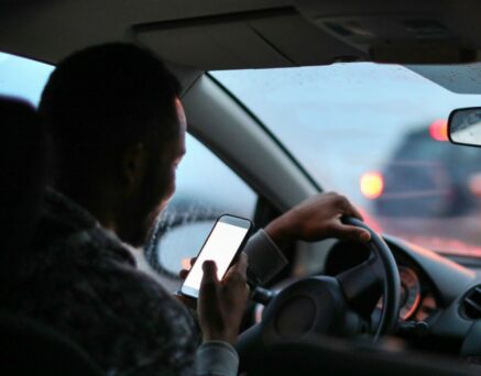 Man using his phone while driving in the rain.