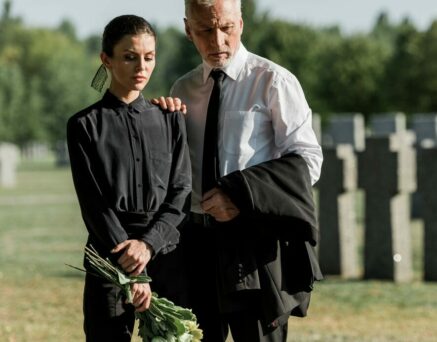 senior man standing with a woman holding flowers on funeral
