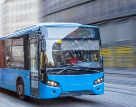 Blue bus moving on the road in city in early morning