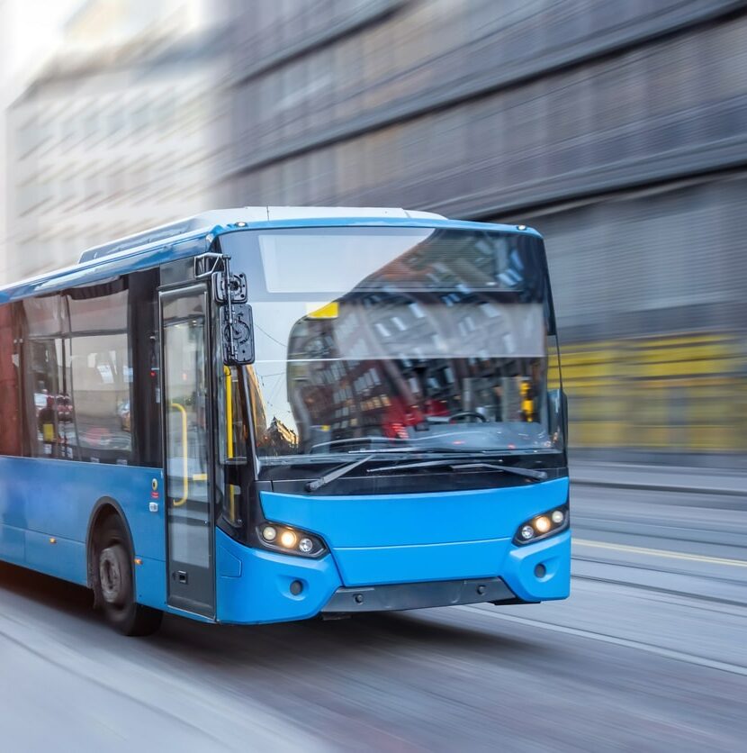 Blue bus moving on the road in city in early morning