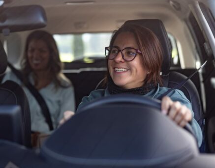female crowdsourced taxi driver talking to a passenger in the back seat and looking through the rear view