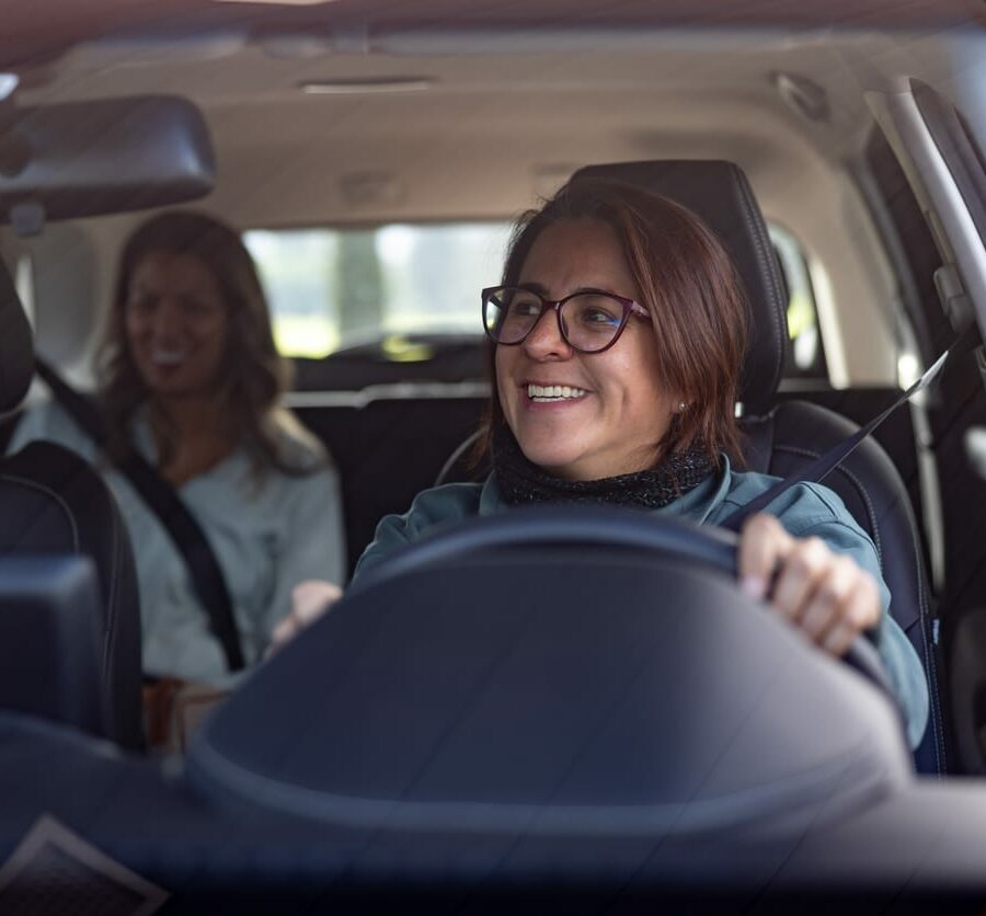 female crowdsourced taxi driver talking to a passenger in the back seat and looking through the rear view