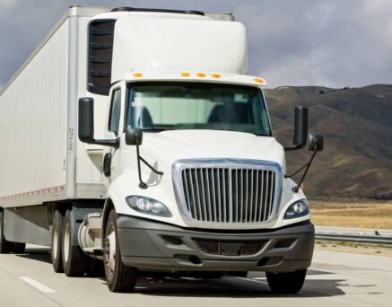 White cargo trucks driving on Interstate 5 in California