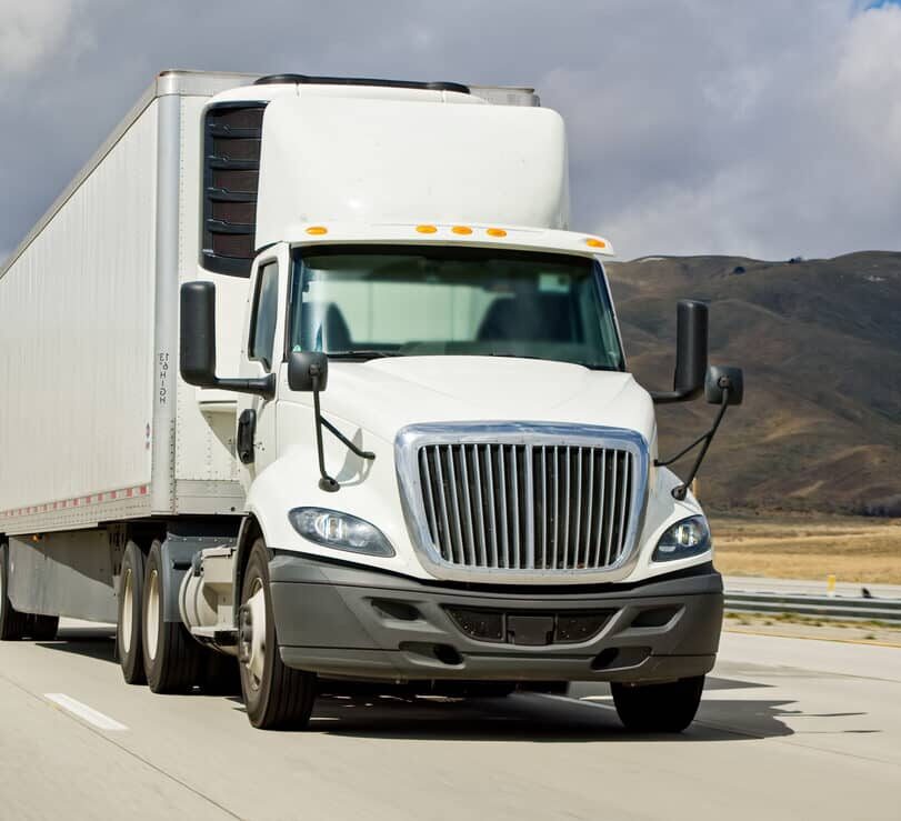 White cargo trucks driving on Interstate 5 in California