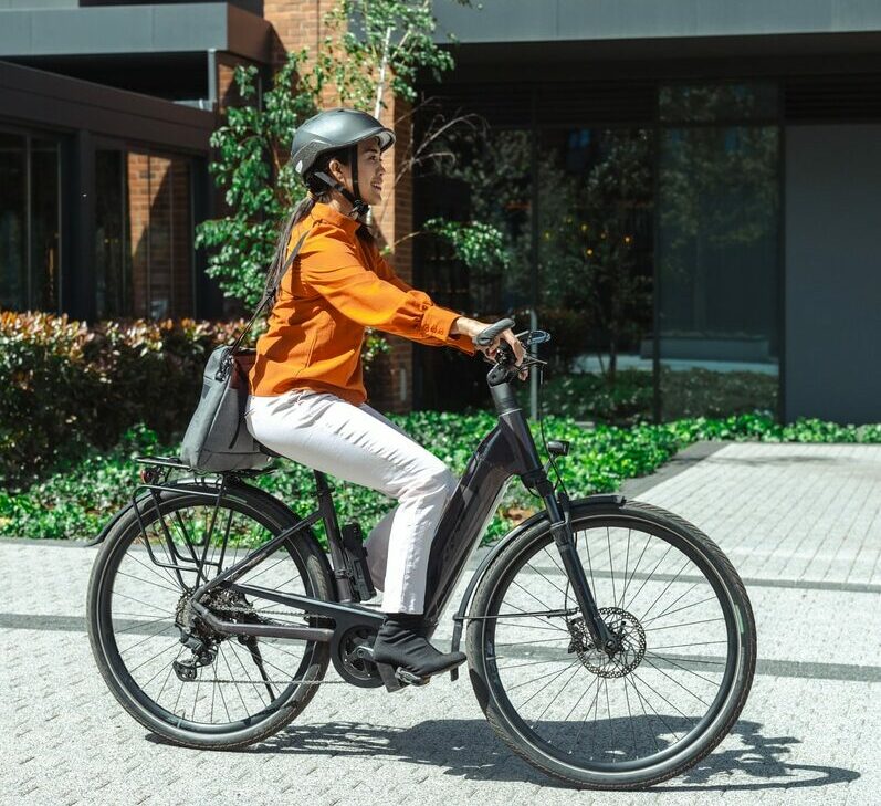 Woman riding an electric bike outside modern urban building during the day